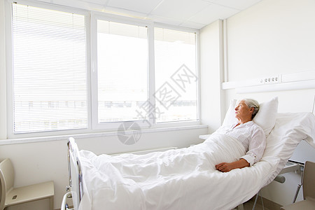 悲伤的老妇女躺医院病房的床上图片