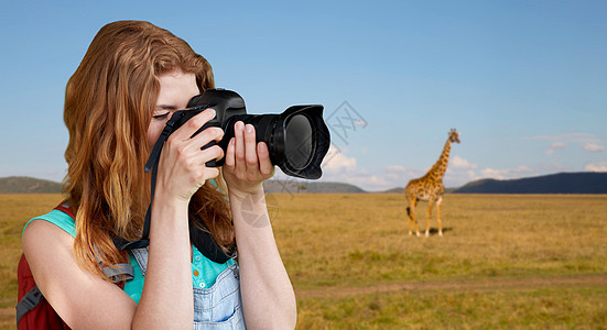 旅行,旅游摄影快乐的轻妇女背包相机拍摄长颈鹿非洲草原背景女人带着背包相机萨凡纳上空女人带着背包相机图片