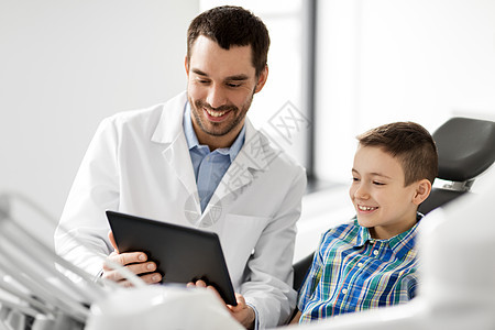 医学,牙科医疗微笑的男牙医向牙科诊所的儿童病人展示平板电脑牙医诊所向儿童病人展示平板电脑牙医诊所向儿童病人图片