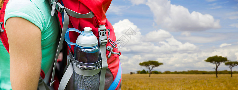 旅行,旅游,徒步旅行人的近距离的女人与水瓶背包口袋非洲热带草原的背景把带水瓶的女人关背包里把带水瓶的女人关图片