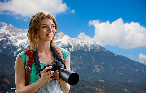 旅行,旅游摄影快乐的轻妇女背包相机拍摄阿尔卑斯山背景女人带着背包相机阿尔卑斯山上女人带着背包相机阿尔图片