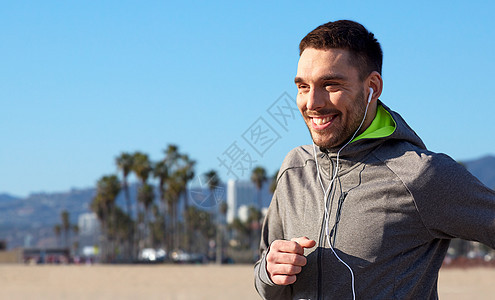 健身,运动技术快乐的人跑步听音乐耳机威尼斯海滩背景加利福尼亚带着耳机跑的快乐男人带着耳机跑的快乐男人图片