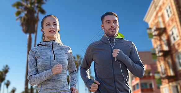健身,运动技术快乐的夫妇跑步听音乐耳机威尼斯海滩背景加利福尼亚夫妇带着耳机跑过威尼斯海滩夫妇带着耳图片