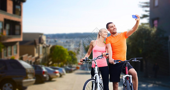 健身,运动,技术健康的生活方式快乐的夫妇骑自行车自拍智能手机旧金山城市背景夫妇骑自行车用智能手机自拍图片