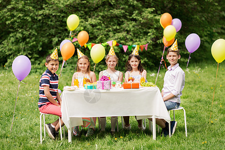 假期,童庆祝快乐的孩子坐桌子上的生日聚会夏季花园快乐的孩子夏季花园的生日聚会上快乐的孩子夏季花园的生日图片