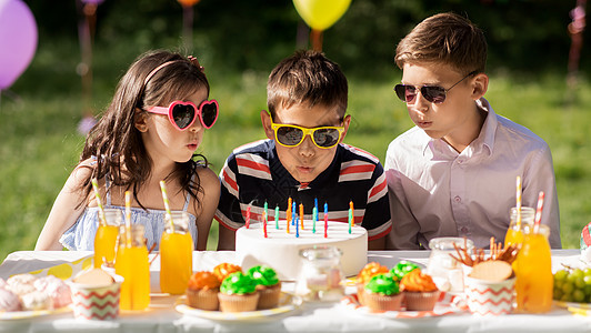 假期,童庆祝快乐的孩子生日蛋糕上蜡烛,坐夏季花园聚会的桌子上快乐的孩子夏天的生日聚会上吃蛋糕快乐的孩子图片