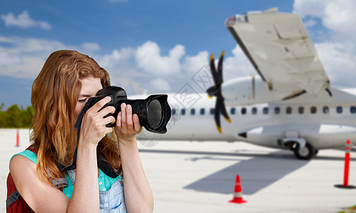 航空旅行,旅游摄影快乐的轻妇女,背包相机飞机上拍摄机场背景旅游妇女飞机上用照相机拍照旅游妇女飞机上用照图片