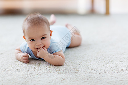可爱的婴儿男孩躺地板上吮吸手指背景图片