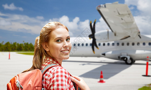 航空旅行,旅游旅行微笑的旅游妇女与背包飞机上的机场背景带背包的旅游妇女乘飞机旅行带背包的旅游妇女乘飞机旅行图片