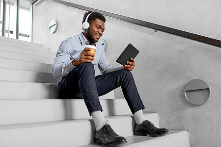 商业,人技术非裔美国商人戴着耳机平板电脑,电脑办公室咖啡休息时听音乐戴耳机平板电脑的商人戴耳机平板电脑的图片
