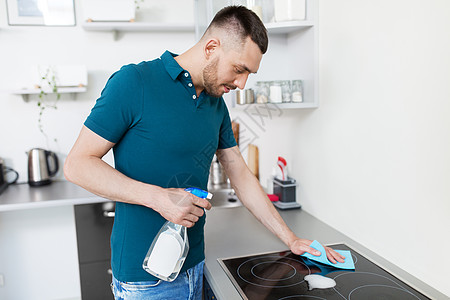 清洁,家庭人的男人与喷雾清洁剂擦布炊具家庭厨房家里厨房里抹布清洁炊具的男人家里厨房里抹布清洁炊具的男人图片