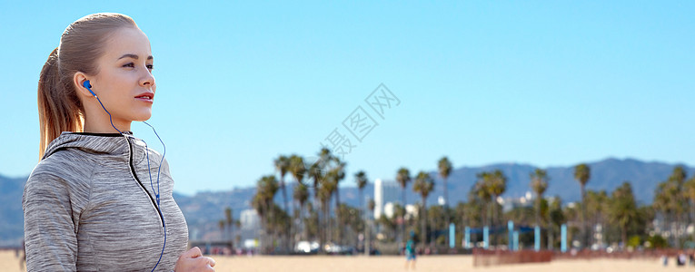 加利福尼亚威尼斯海滩背景上女人戴着耳机听音乐跑步图片