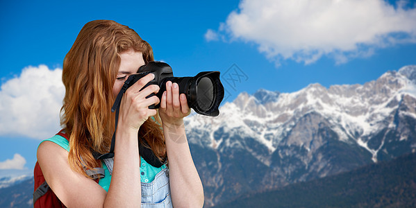 旅行,旅游摄影快乐的轻妇女背包相机拍摄阿尔卑斯山背景女人带着背包相机阿尔卑斯山上女人带着背包相机阿尔图片