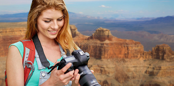 旅行,旅游摄影快乐的轻妇女背包相机拍摄大峡谷公园的背景大峡谷带背包照相机的女人大峡谷带背包照相图片