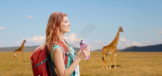 冒险,旅行,旅游,徒步旅行人们的微笑的轻女人带着背包瓶水长颈鹿非洲草原的背景快乐的女人带着背包非洲草原上图片