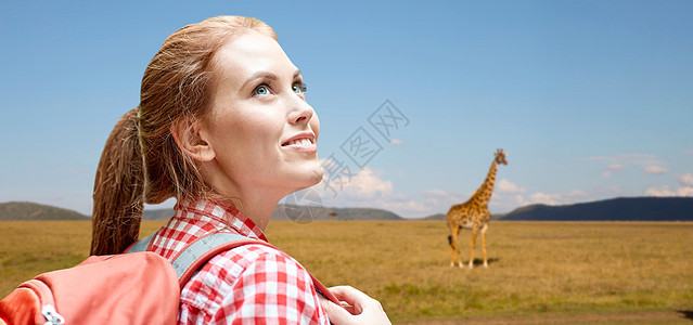 冒险,旅行,旅游,徒步旅行人的微笑的轻女人带着背包长颈鹿非洲草原背景快乐的女人带着背包非洲草原上快乐的女图片