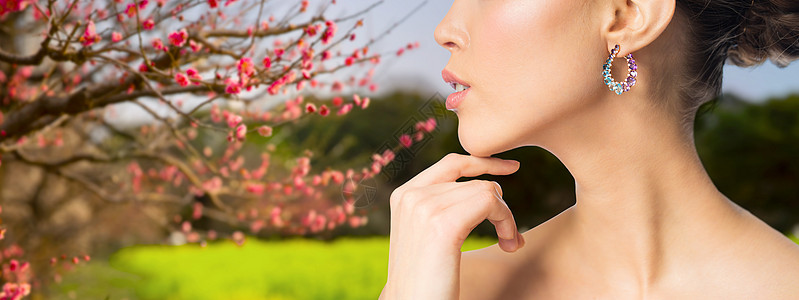 美丽,珠宝豪华美丽的女人脸与耳环自然春天樱花背景用耳环遮住美丽的女人的脸用耳环遮住美丽的女人的脸图片