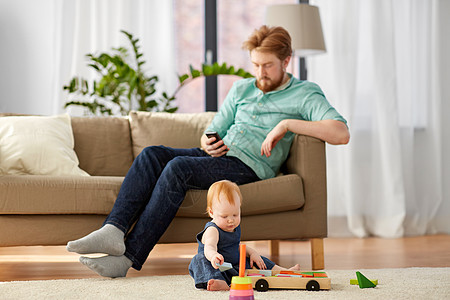 家庭,父亲人的快乐的红头发父亲与智能手机小宝贝女儿玩玩具积木套件家里爸爸宝宝家玩玩具积木爸爸宝宝家玩图片