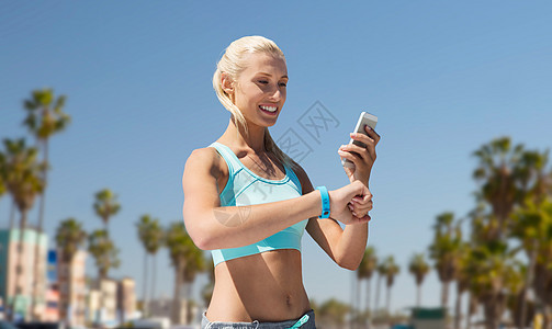 运动,技术健康的生活方式微笑的轻妇女与健身跟踪智能手机锻炼威尼斯海滩背景加利福尼亚快乐的女人健身追踪器智图片