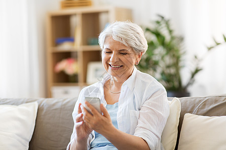 技术,沟通人的快乐的老年女子与智能手机家里快乐的高级女人家里智能手机图片