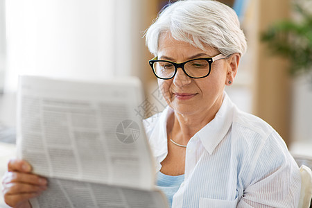 中老年妇女在家阅读报纸背景图片