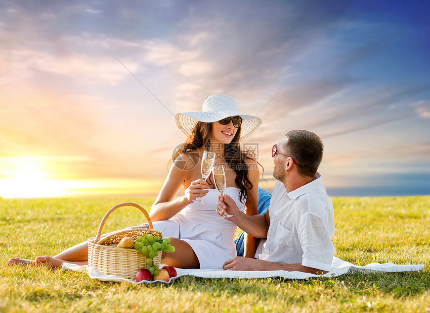 ‘~爱情,约会,人庆祝的微笑的夫妇草地上的日落天空背景上野餐时喝香槟微笑的夫妇野餐时喝香槟  ~’ 的图片
