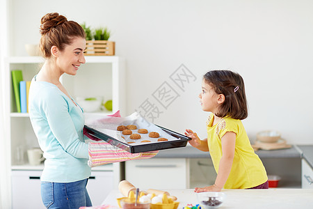 家庭,烹饪人的快乐的母亲着托盘的饼干小女儿家里的厨房快乐的母亲女儿家烤饼干图片