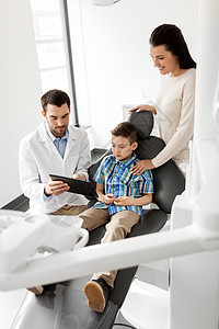 医学,牙科医疗保健牙医向儿童病人他的母亲牙科诊所展示平板电脑牙医牙科诊所向孩子展示平板电脑图片