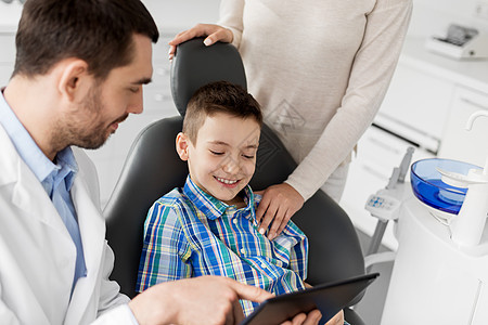 医学,牙科医疗保健牙医向儿童病人他的母亲牙科诊所展示平板电脑牙医牙科诊所向孩子展示平板电脑图片