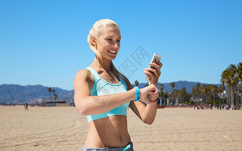 运动,技术健康的生活方式微笑的轻妇女与健身跟踪智能手机锻炼威尼斯海滩背景加利福尼亚快乐的女人健身追踪器智图片