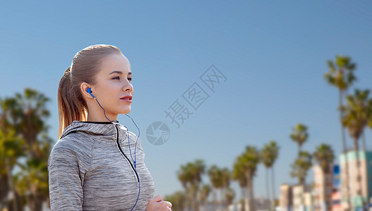 健身,运动技术快乐的女人跑步听音乐耳机威尼斯海滩背景加利福尼亚戴着耳机威尼斯海滩上跑的女人图片