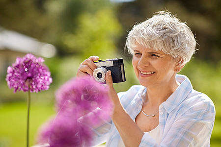 摄影,休闲人的快乐的老年女子与相机拍摄花开夏季花园带着相机拍照花的高级女人图片