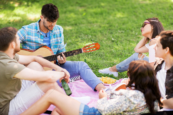 友谊,休闲夏季群快乐的微笑朋友与吉他非酒精啤酒冷野餐毯夏季公园朋友们夏天的公园野餐时弹吉他图片