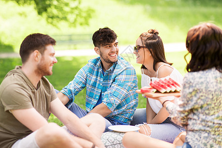 友谊休闲夏天的群快乐的朋友公园野餐时吃西瓜快乐的朋友夏天野餐时吃西瓜图片