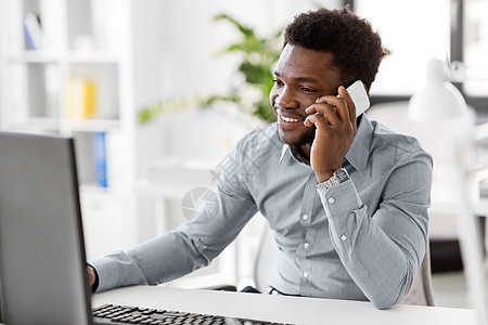 商业,人,通信技术微笑的非裔美国商人与电脑呼叫智能手机办公室商人办公室打电话给智能手机图片