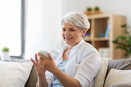 技术,沟通人的快乐的老年女子与智能手机家里快乐的高级女人家里智能手机图片