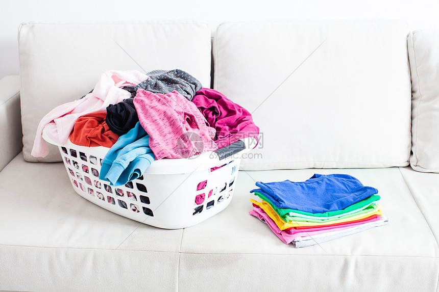 篮子里洗衣服,沙发上放叠干净的亚麻布五颜六色的干净衣服图片