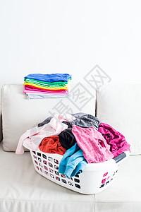 篮子里洗衣服,沙发上放叠干净的亚麻布五颜六色的干净衣服图片