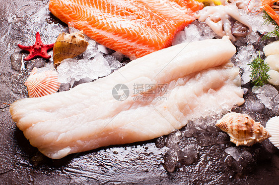 海鲜冰上,鳕鱼片棕色的石板背景上冰上的海鲜图片