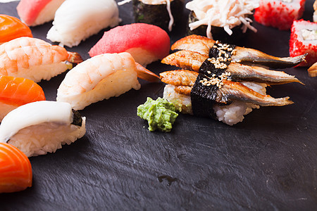 特写四套寿司与鲑鱼,金鱼,扇贝虾黑色背景套四个寿司图片