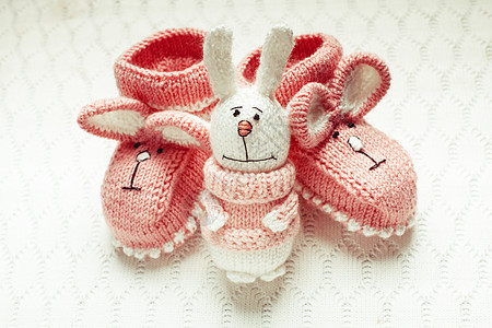 针粉红色婴儿靴与兔子口吻纺背景针婴儿靴图片
