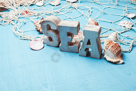 美丽的海洋构图,木制字母蓝色背景上的渔网海洋内部装饰图片