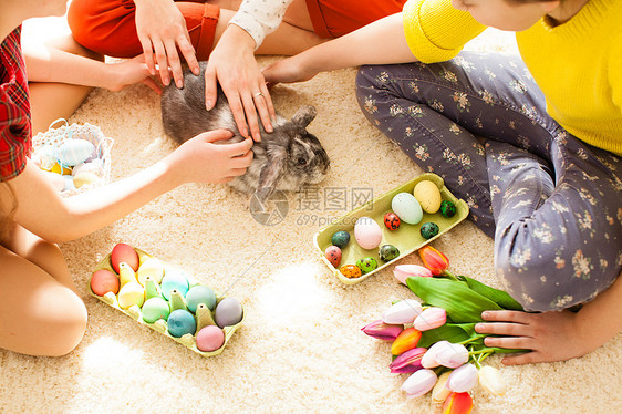 穿着兔子耳朵的女朋友坐地板上玩复活节兔子假期准备的女朋友玩兔子图片