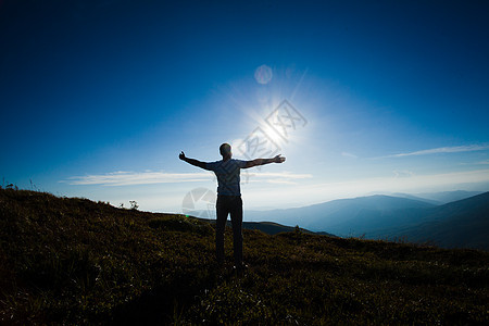 山顶日落时举双手的人的剪影享受自由的人图片