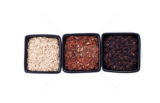 各种类型的非白米黑色碗中分离白色上各种类型的大米图片