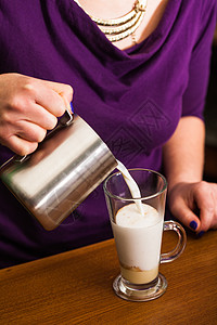 咖啡师正把牛奶倒进个杯子里,杯子里放着焦糖制的甜辣咖啡铁咖啡师正准备铁图片