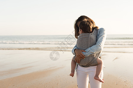 妈妈带着孩子母亲带着麦格宝宝海滩上抱着蹒跚学步的孩子图片