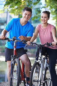 城市环境中轻夫妇骑自行车河边的肖像图片