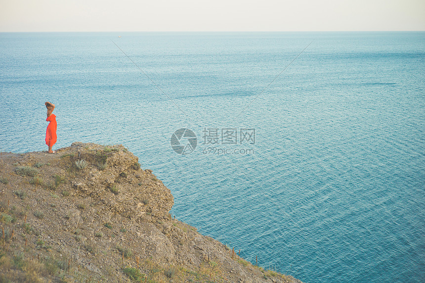 户外生活方式照片的女人穿着红色的衣服看着大海旅行背景旅游业图片