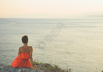 户外生活方式照片的女人穿着红色的衣服看着大海旅行背景旅游业图片